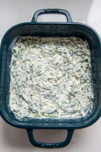 spinach artichoke dip in a green baking dish